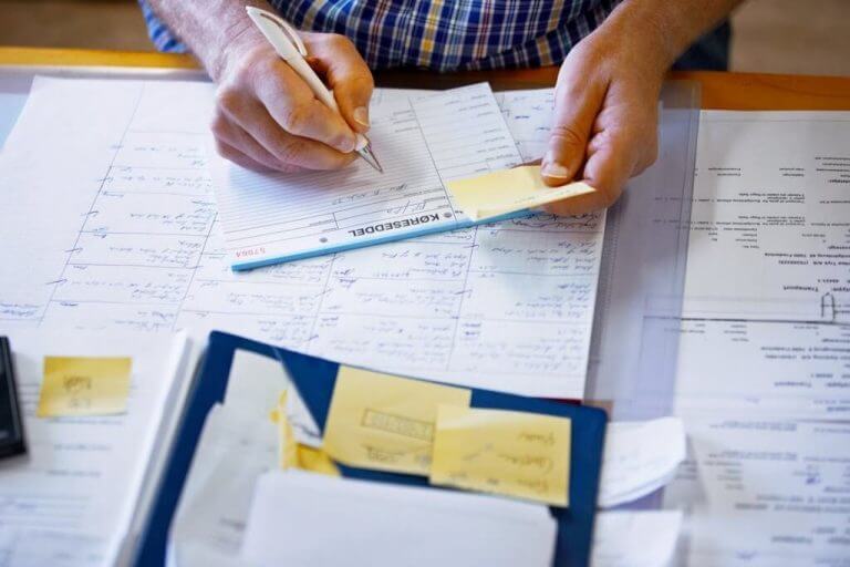 hands writing notes on top of other papers Balancing Balance Sheet for corporations ATS Accounting Edmonton